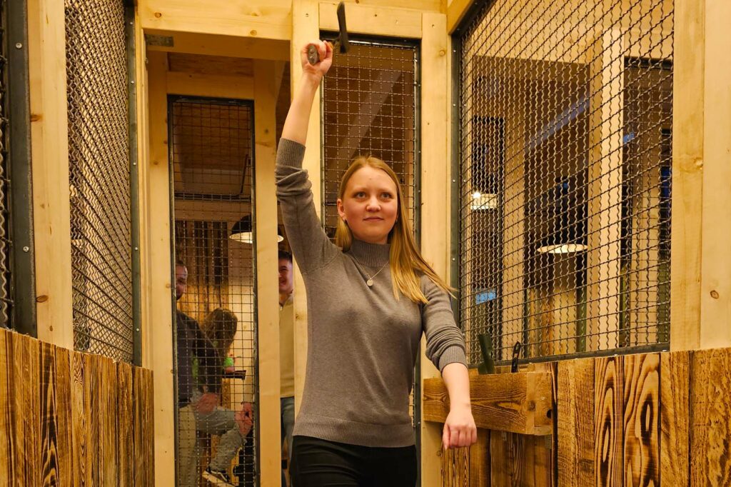 A group of friends at an axe throwing facility, a new trendy place where people can get together for fun and drinks.